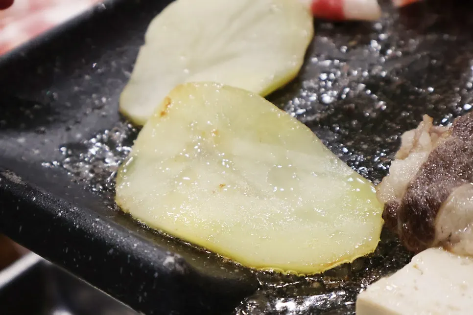 Grill with tofu, potatoes, and pink sausage cooking together