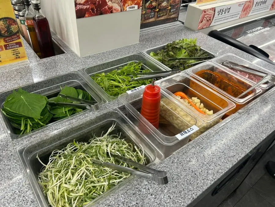Self-serve bar with lettuce, perilla leaves, scallions, and more