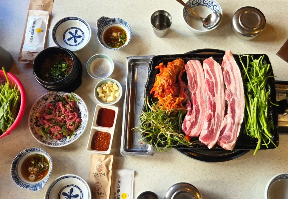 Three chunks of pork belly with minari, scallion strips, and kimchi