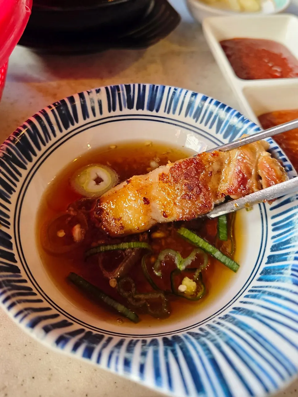 Pork belly served with grilled minari and scallion strips