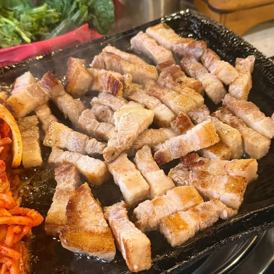 Pork belly cooking on a cast-iron grill