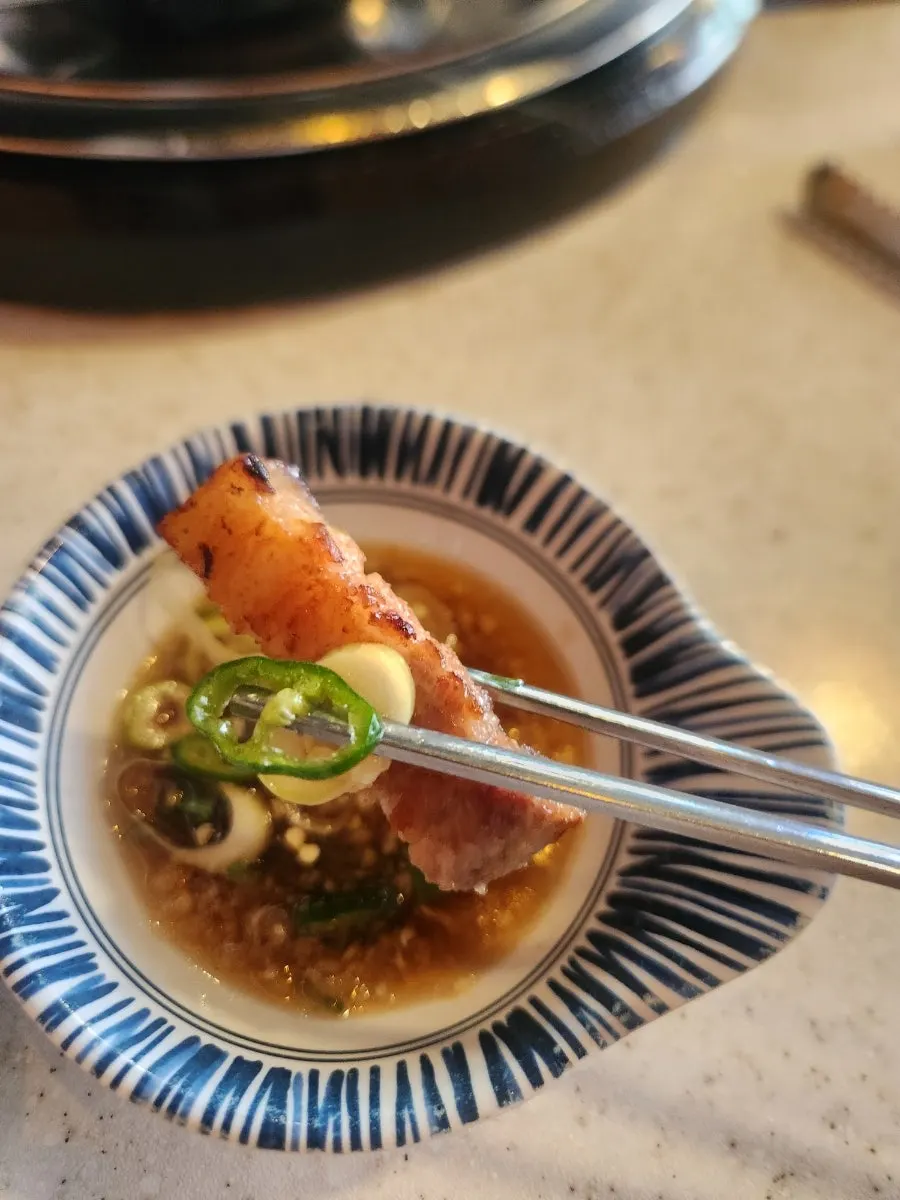 A thick slice of pork belly dipped in garlic sauce