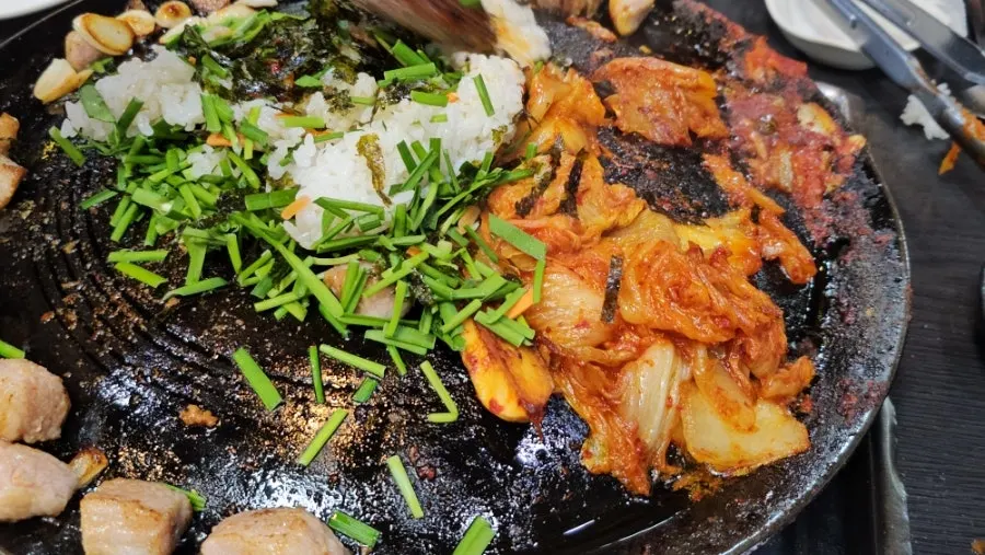 Kimchi and rice added to the cauldron lid for fried rice