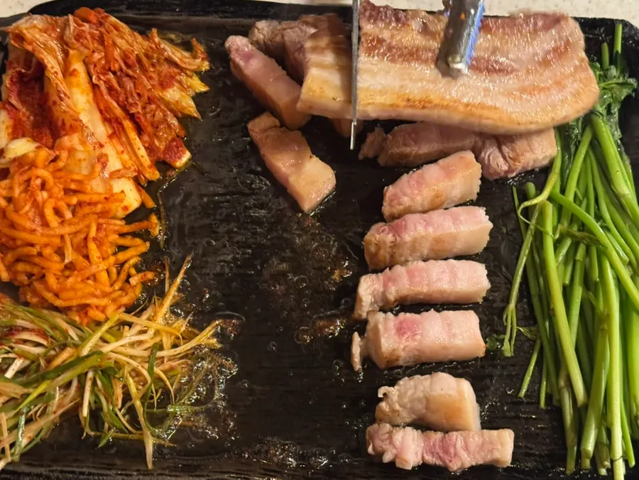 불판에서 구워지는 돈 삼겹살과 곁들임 찬