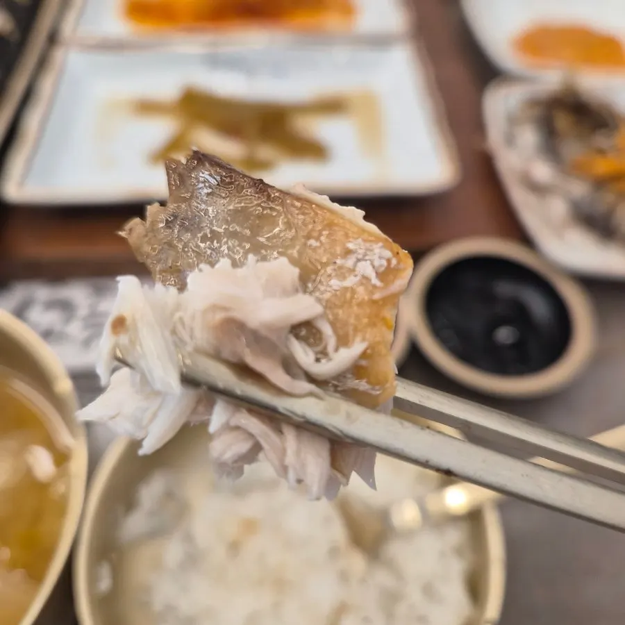 A piece of grilled eel picked up with chopsticks