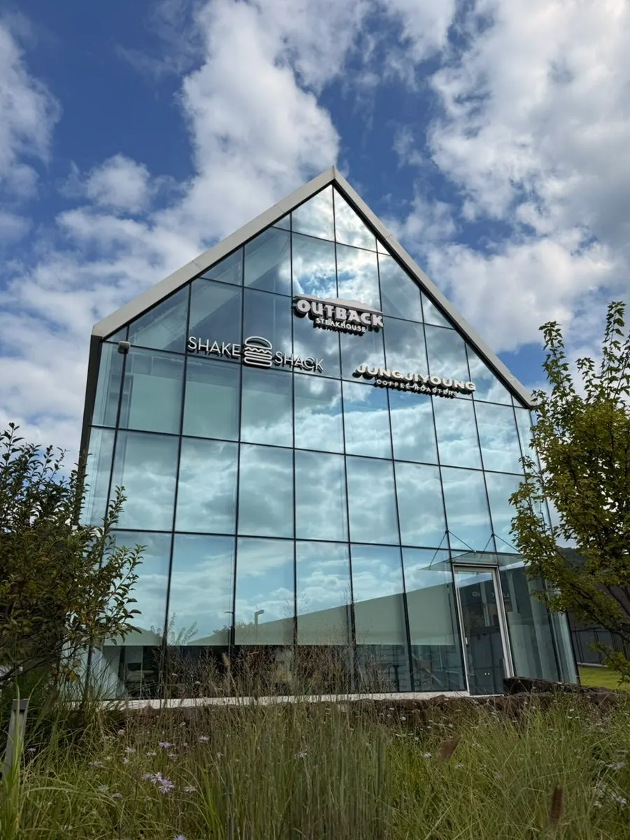 Triangle-roofed glass building on the hill behind the kids' play area