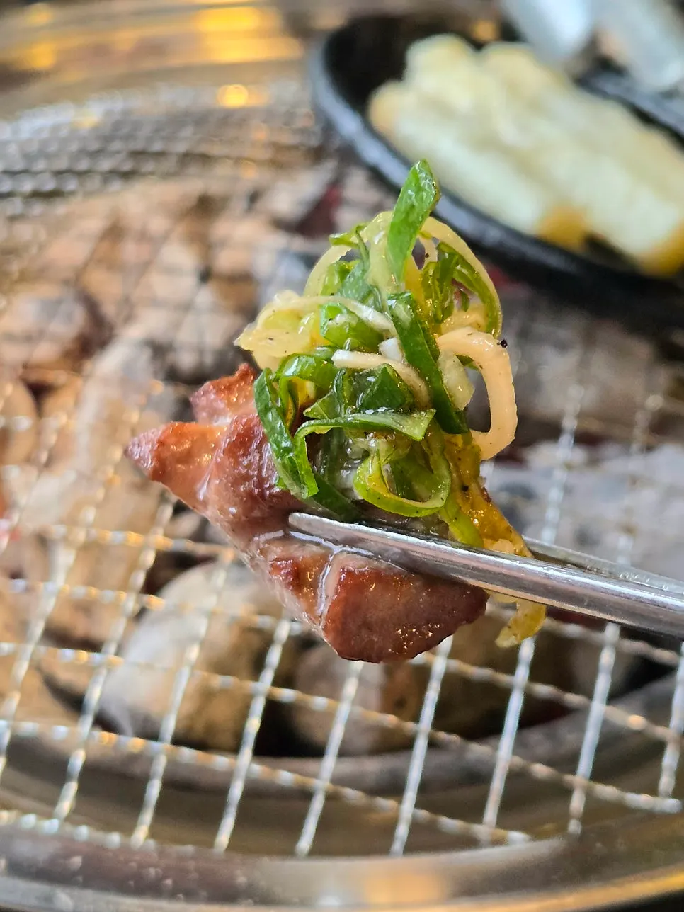 A grilled piece of beef tongue topped with scallion salad