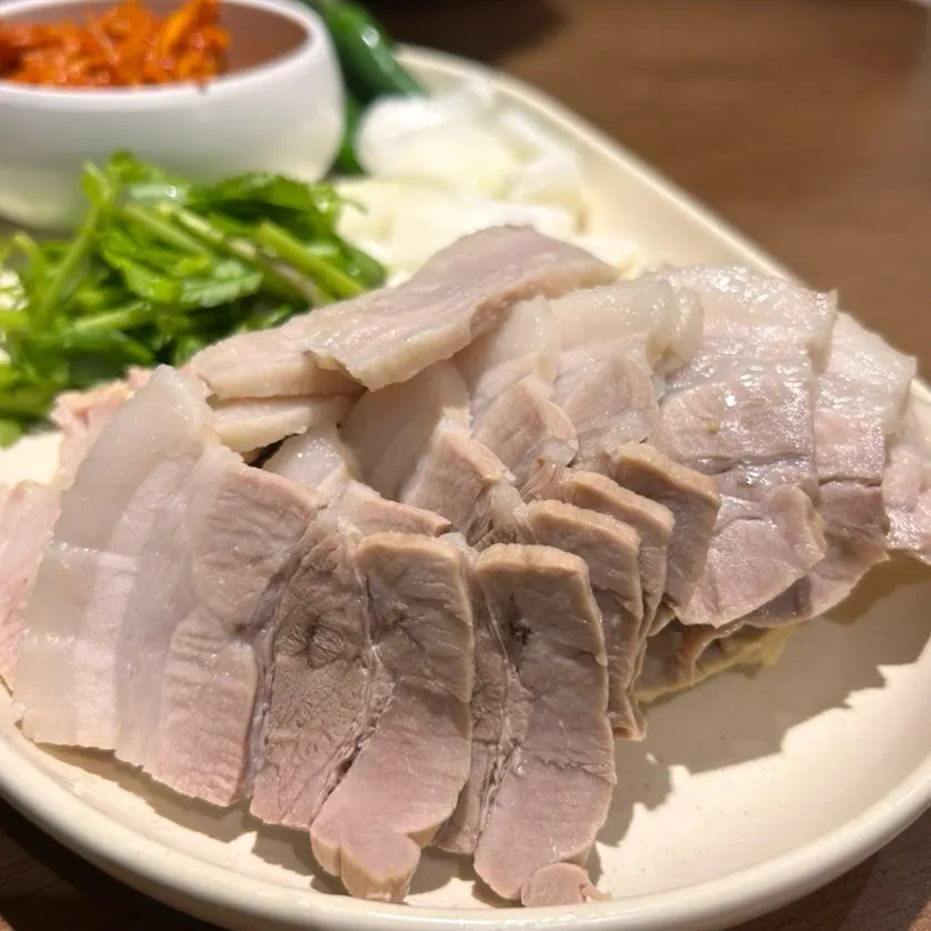 A piece of bossam dipped in sesame soy sauce