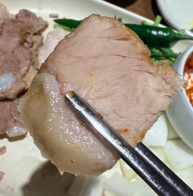 A piece of boiled pork picked up with chopsticks