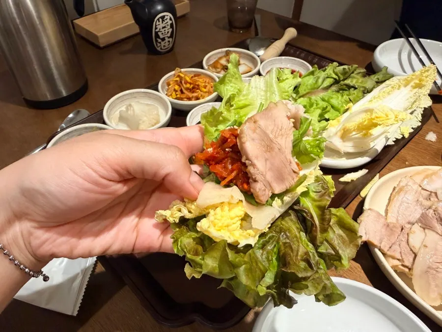 A piece of bossam pork topped with a side dish