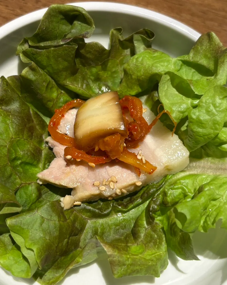 A wrap of pork jowl topped with minari and garlic
