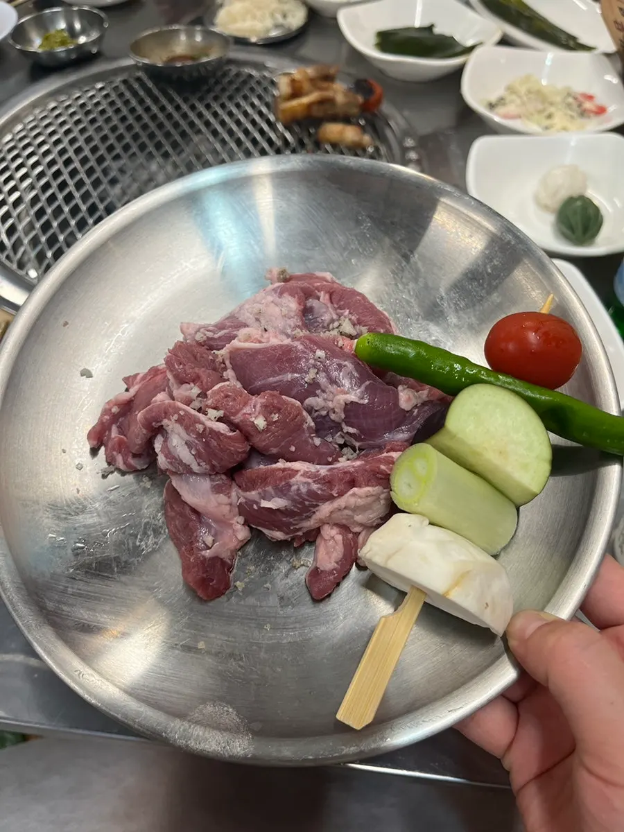 Table spread of raw black pork galmaegisal with vegetable skewers