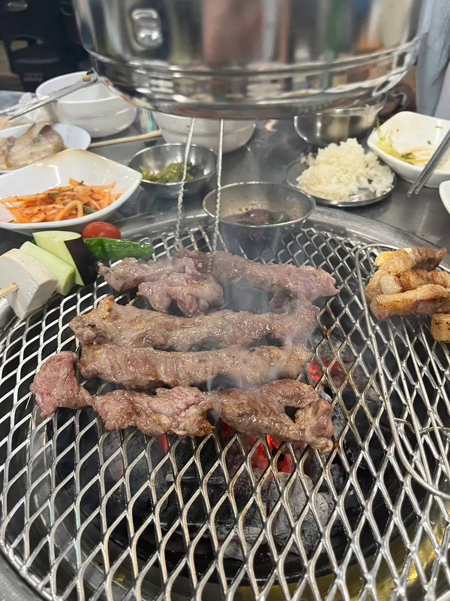 Galmaegisal grilling alongside vegetable skewers