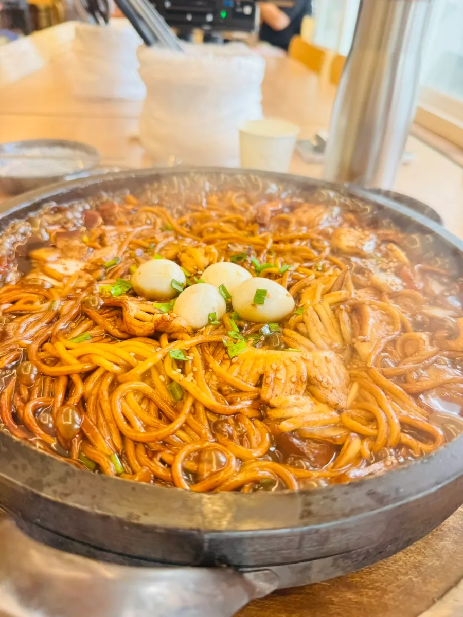 Table setting with steaming scorched rice stone jajangmyeon and stone jjamppong