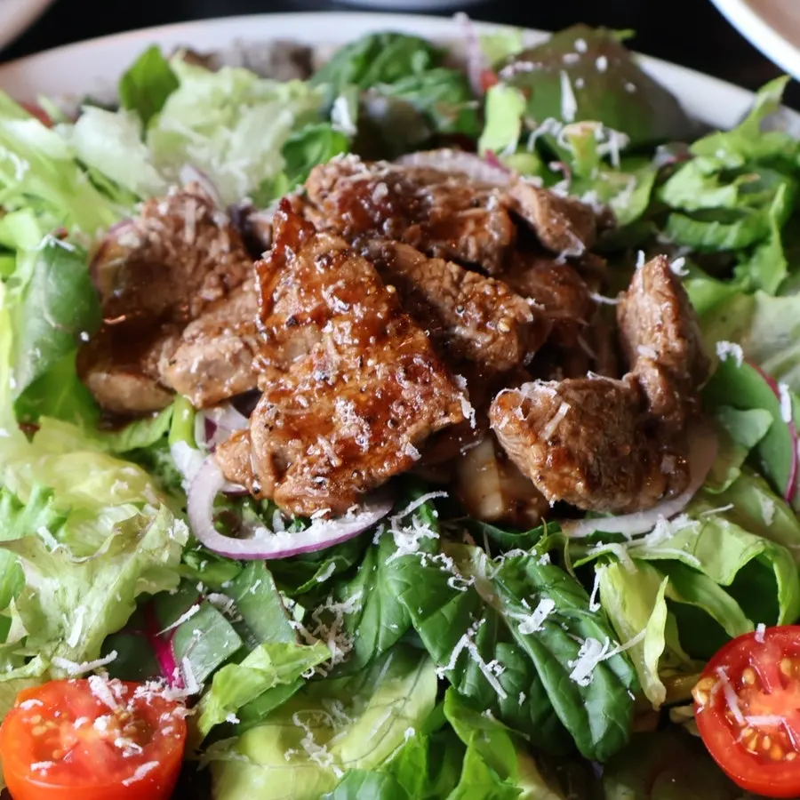 Pizza topped with salad greens and steak