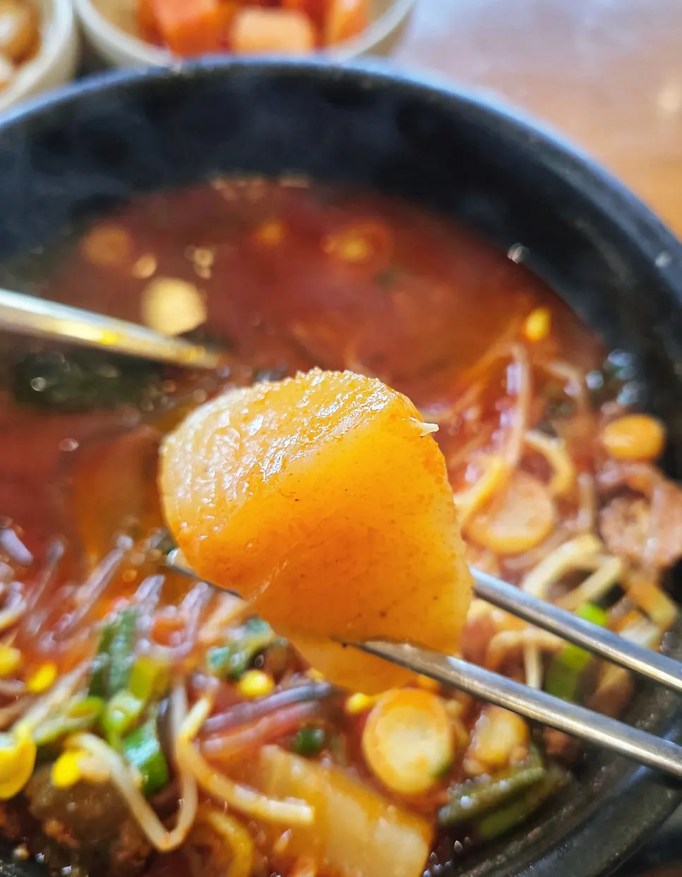 A spoonful of haejangguk topped with diced radish kimchi