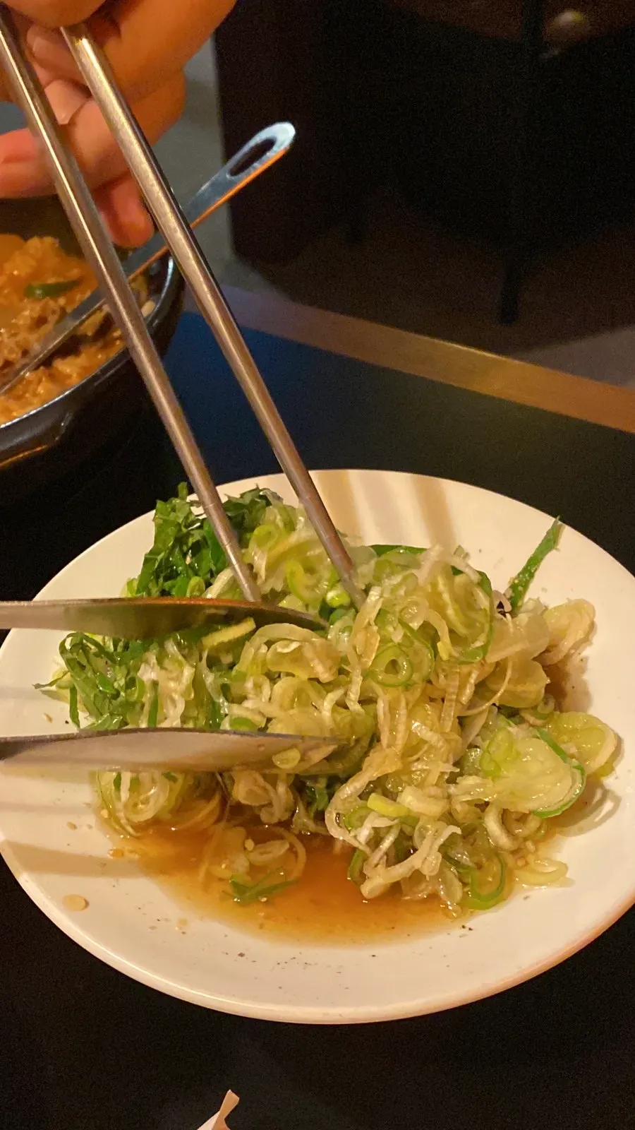 Green onion pile with sauce alongside grilled meat