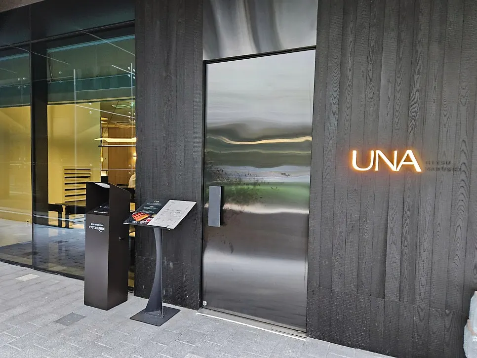 Una Magok exterior with the UNA logo on a black wood-tone wall