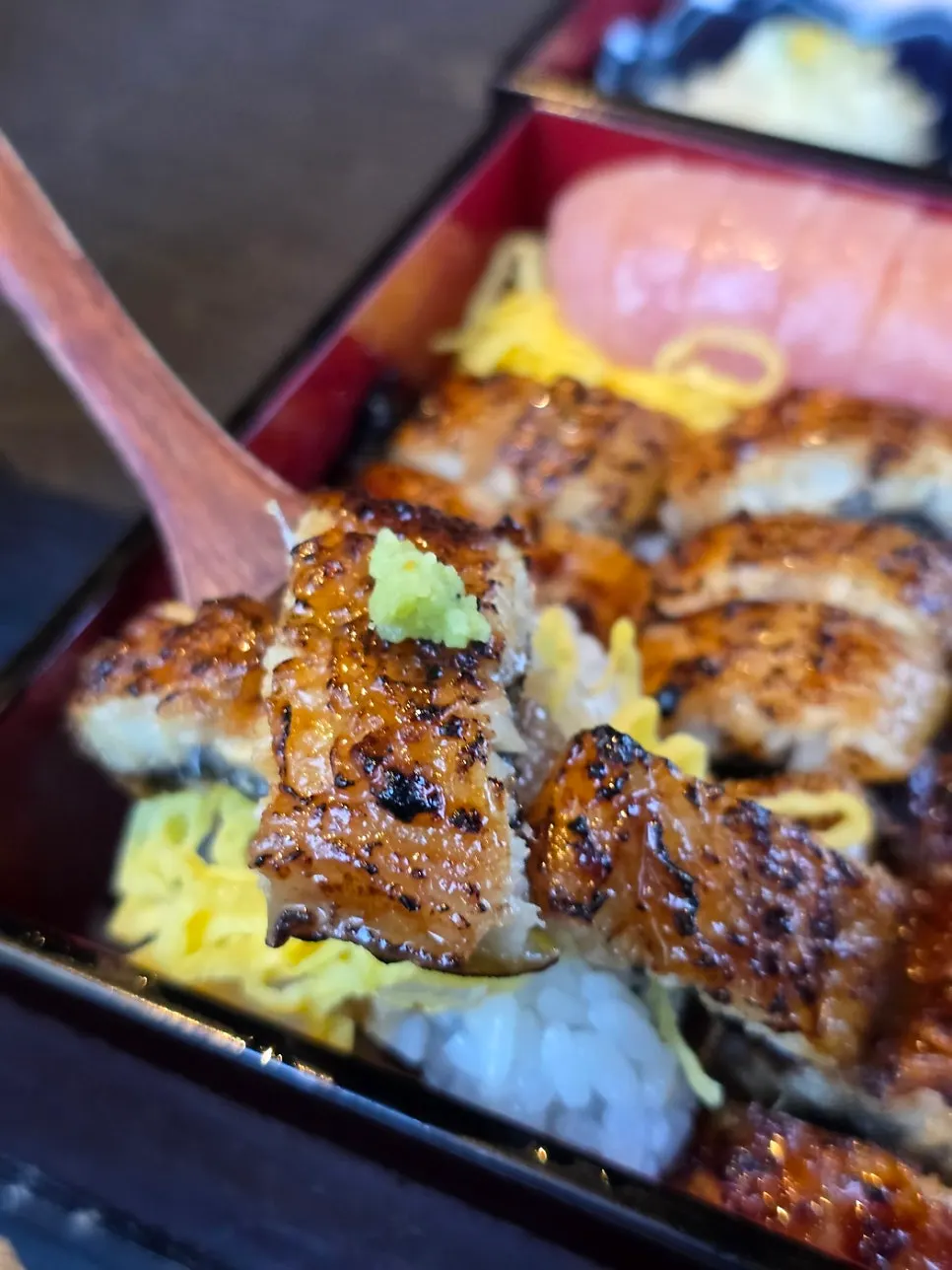 A portion of eel rice bowl with wasabi and green onion