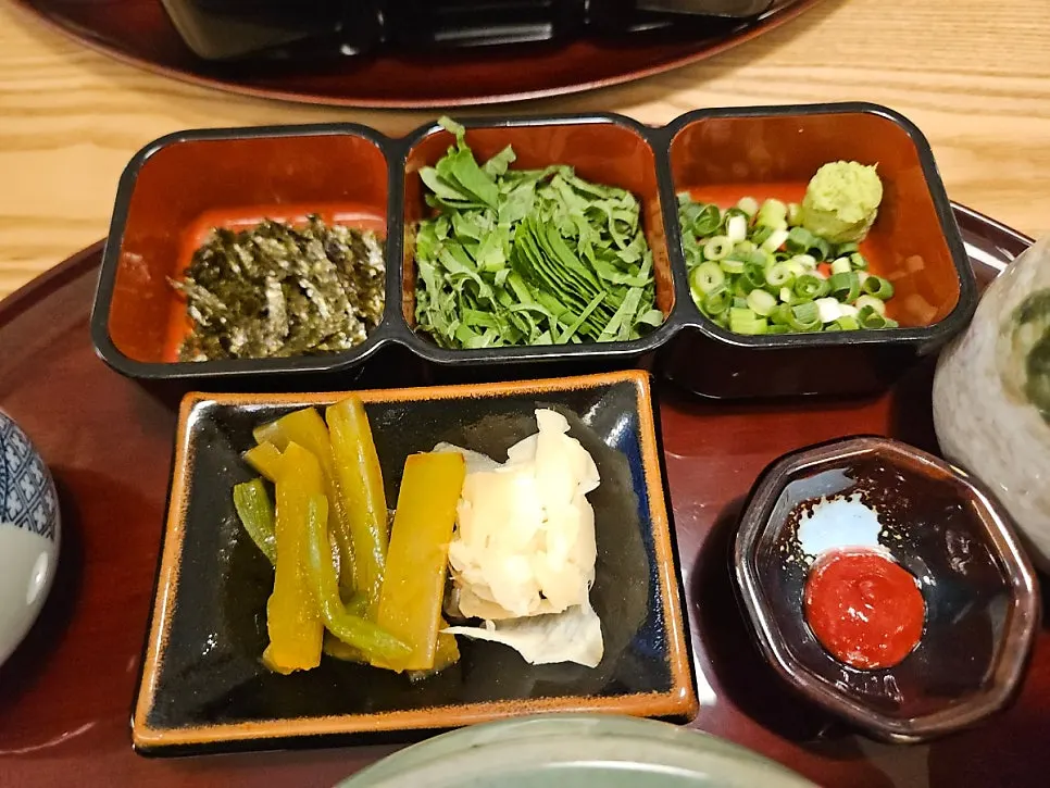 Garnishes of seaweed flakes, perilla, scallion, wasabi, and side dishes