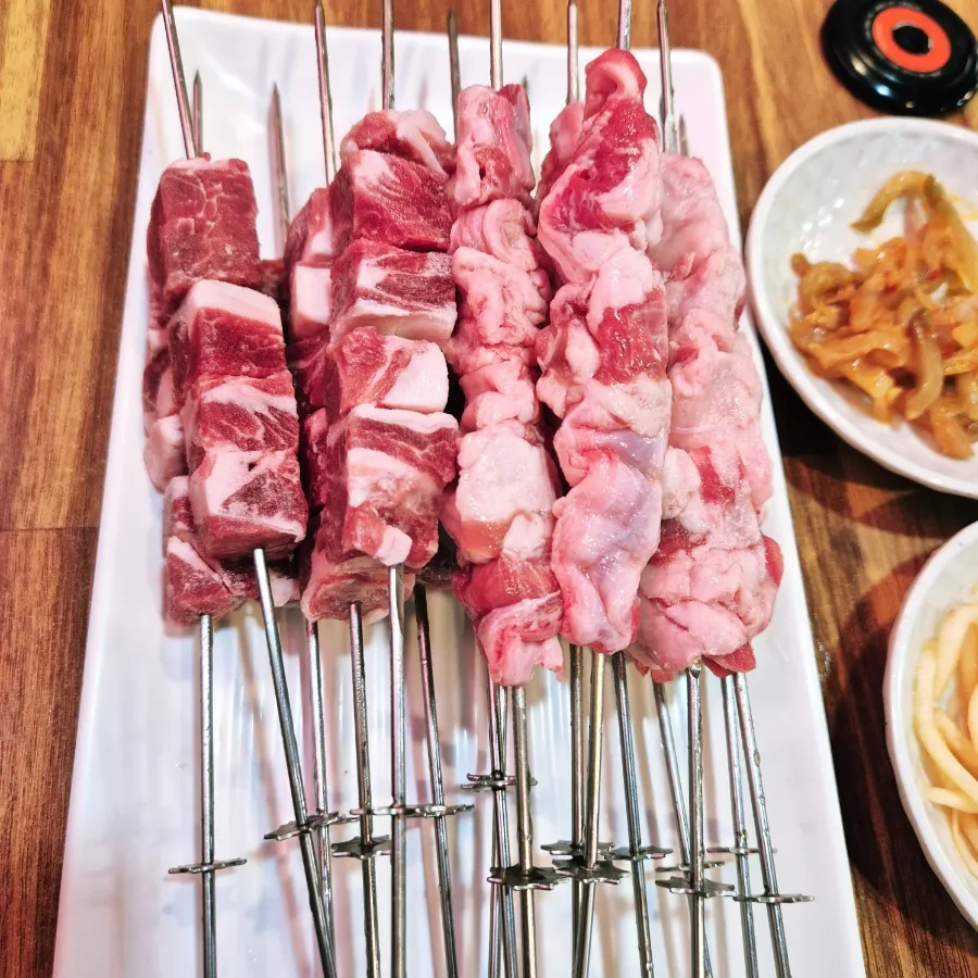 Raw yang kkochi skewers placed on the grill