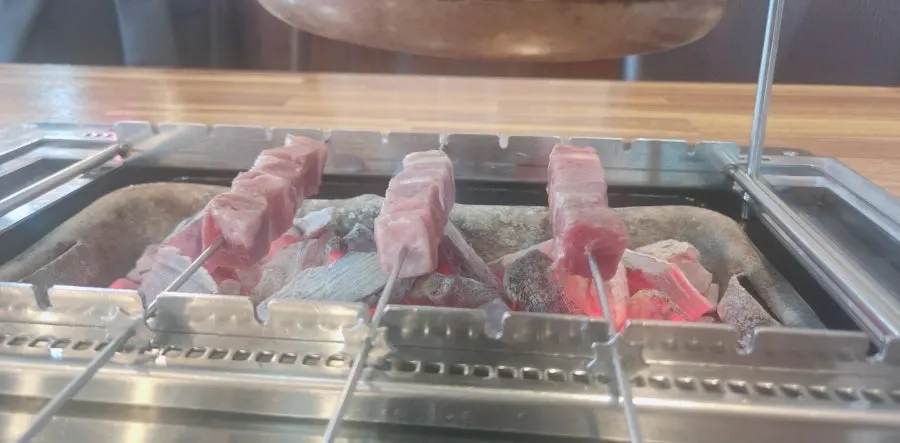 Skewers placed one by one onto the charcoal grill