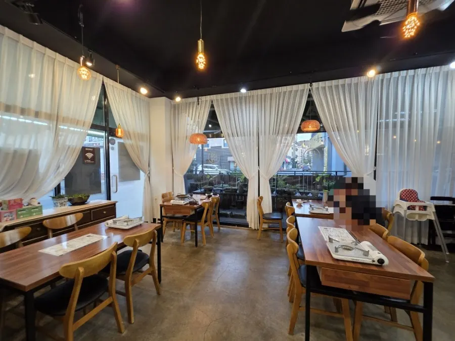 Dining hall seating with large windows and white curtains