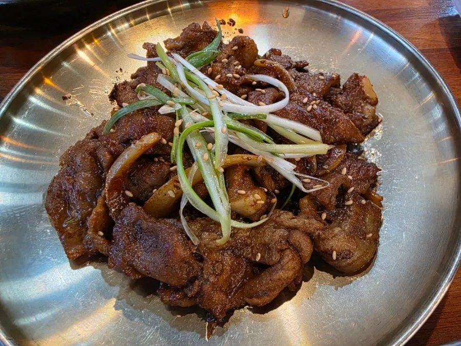 A plate of pork bulgogi topped with scallion strips