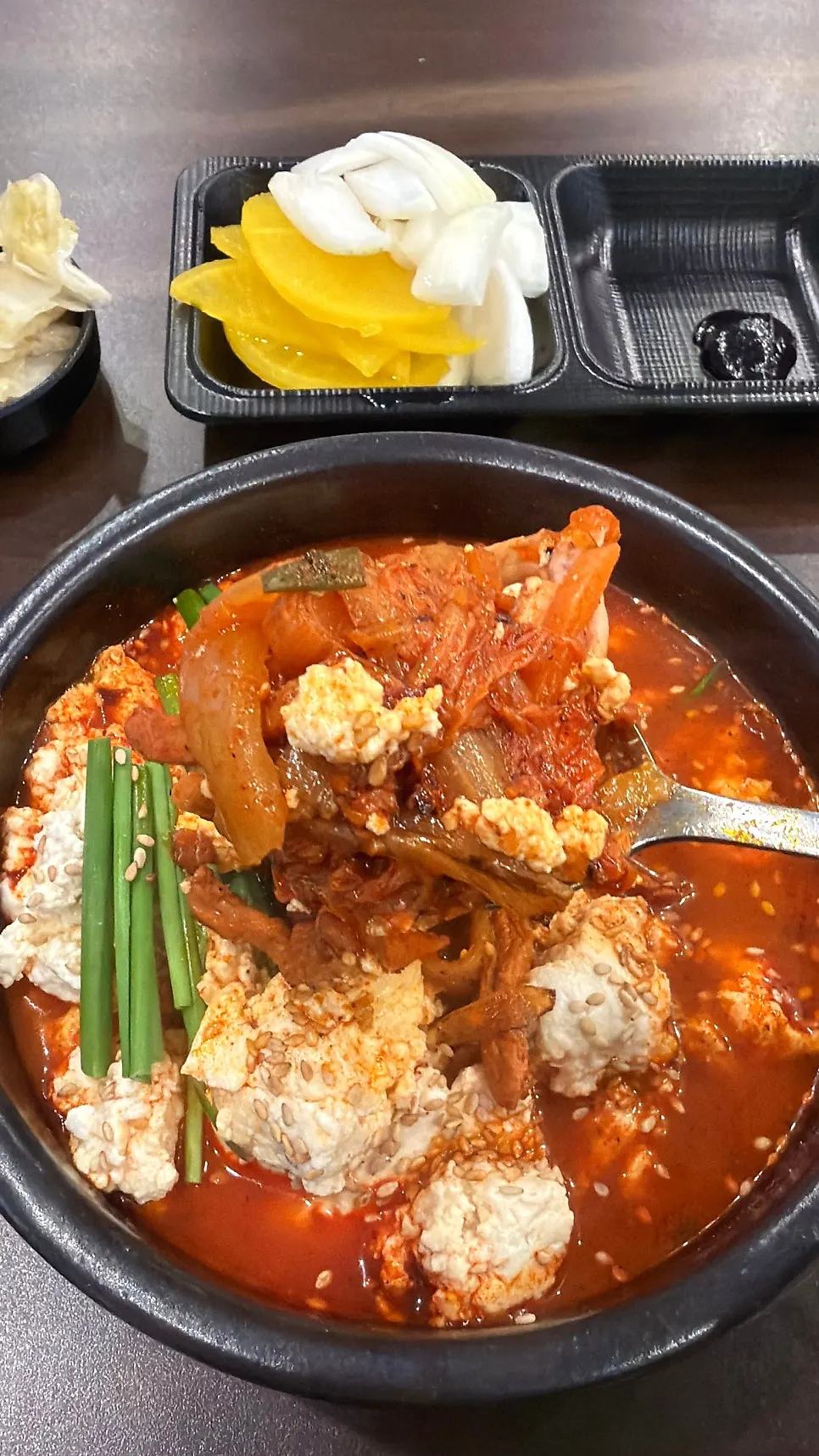 Spoonful overflowing with tofu and seafood