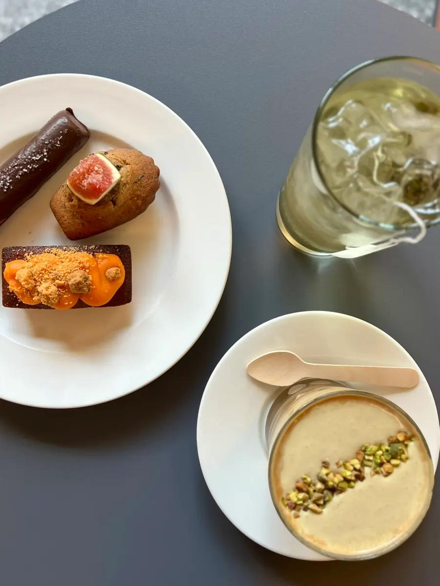 Two financiers, a madeleine, tea and a cream latte laid out together
