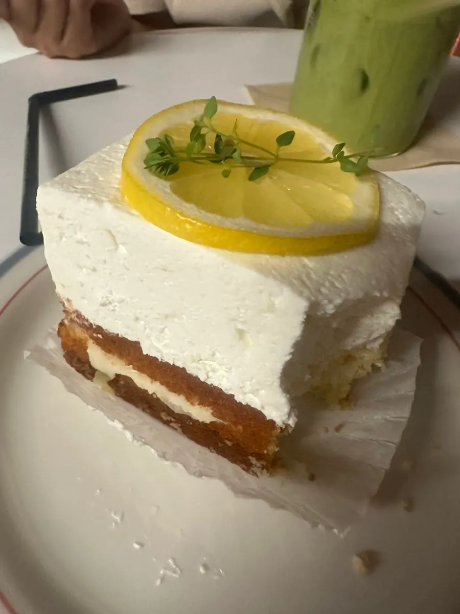 A slice of lemon cake served alongside a drink