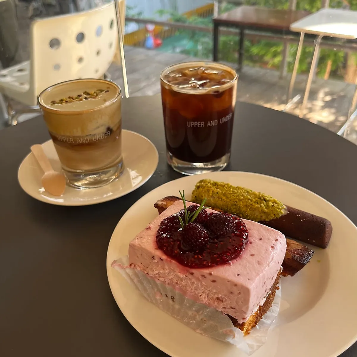A spread of americano, pistachio cream latte, and raspberry cake