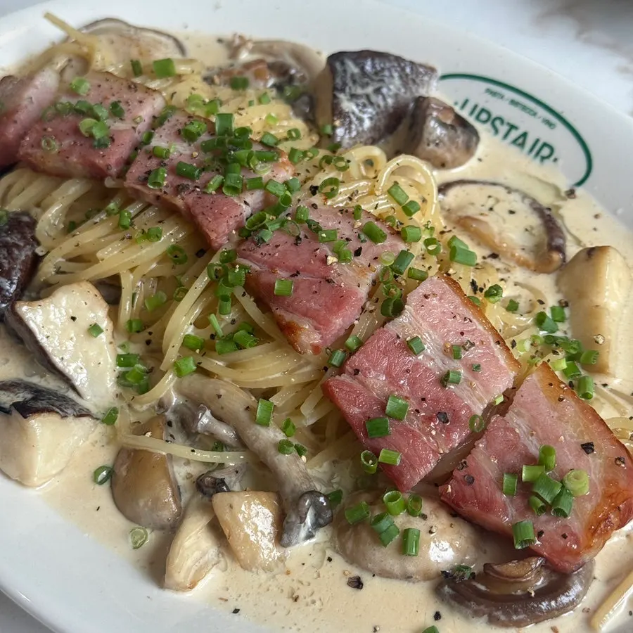Mushroom cream pasta topped with whole bacon and mushrooms