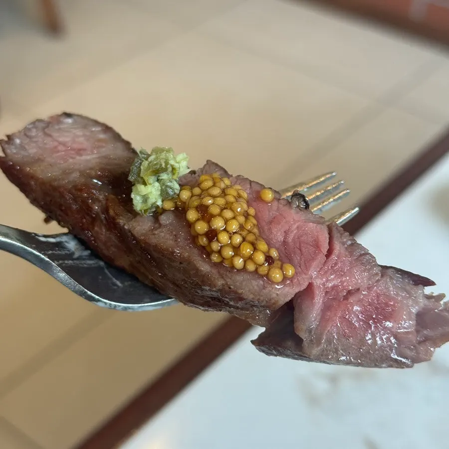 A bite of steak paired with house-made whole grain mustard