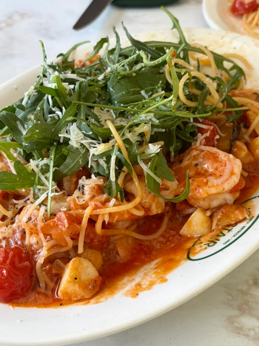 Close-up of shrimp tomato pasta topped with arugula
