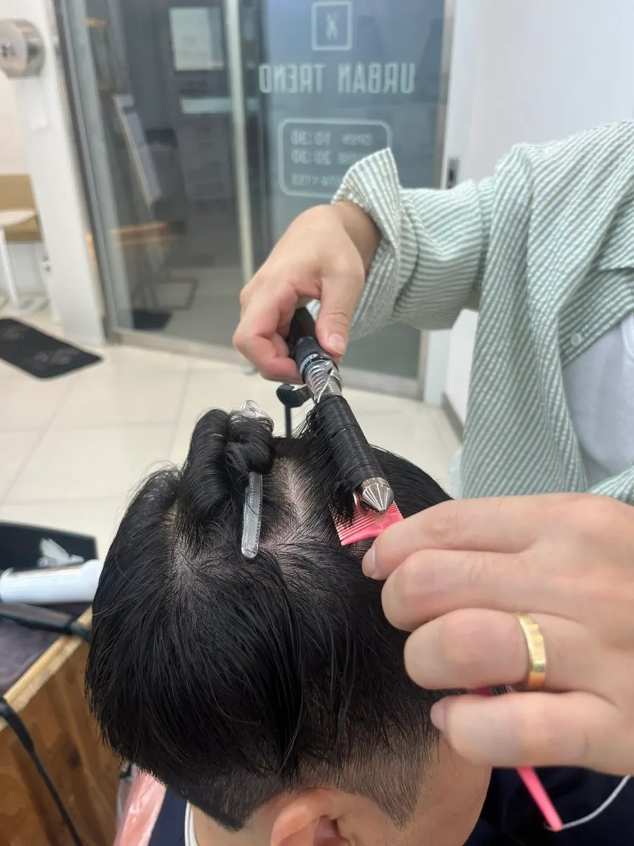 아이롱으로 컬 방향 잡는 시술 장면