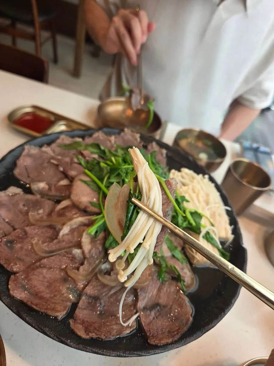 A piece of Korean beef suyuk picked up with chopsticks