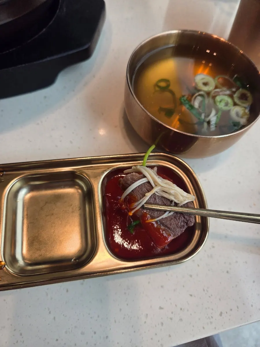 A piece of Korean beef suyuk dipped in the sauce