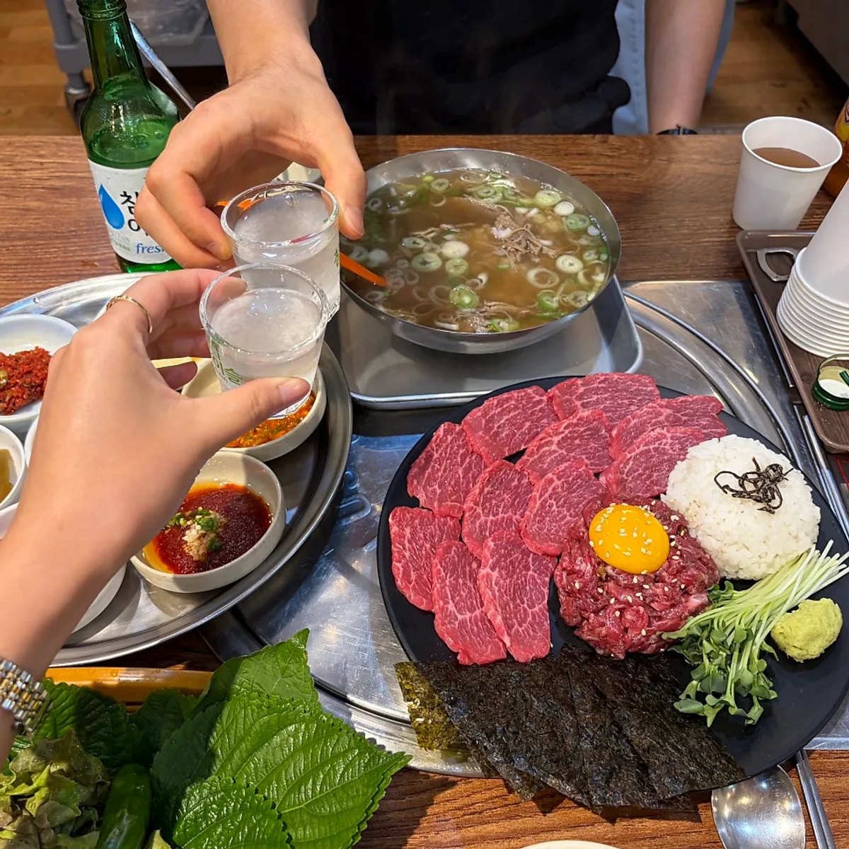 Bàn ăn với platter yukhoe-sashimi và canh cơm thịt bò tại Usijang Hoegwan