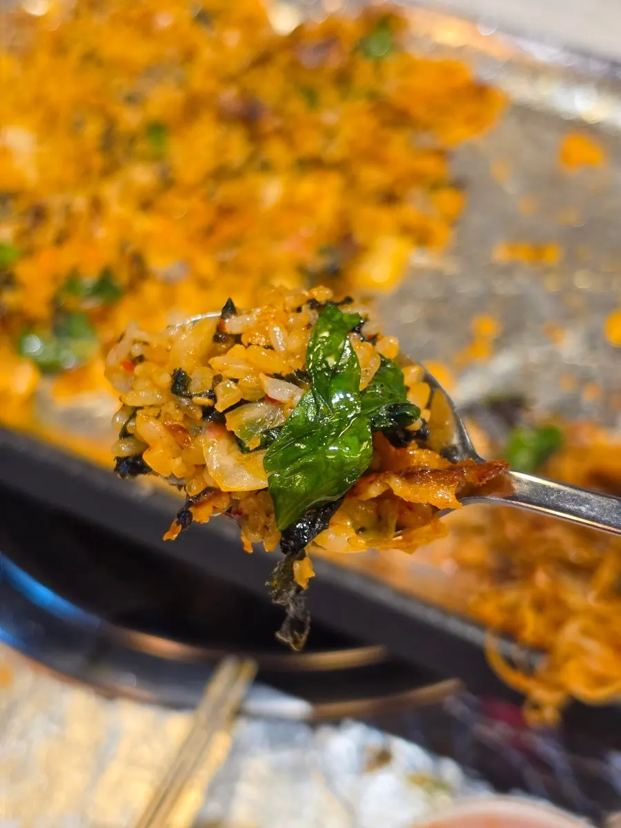 Fried rice spread thin on the grill to cook off moisture
