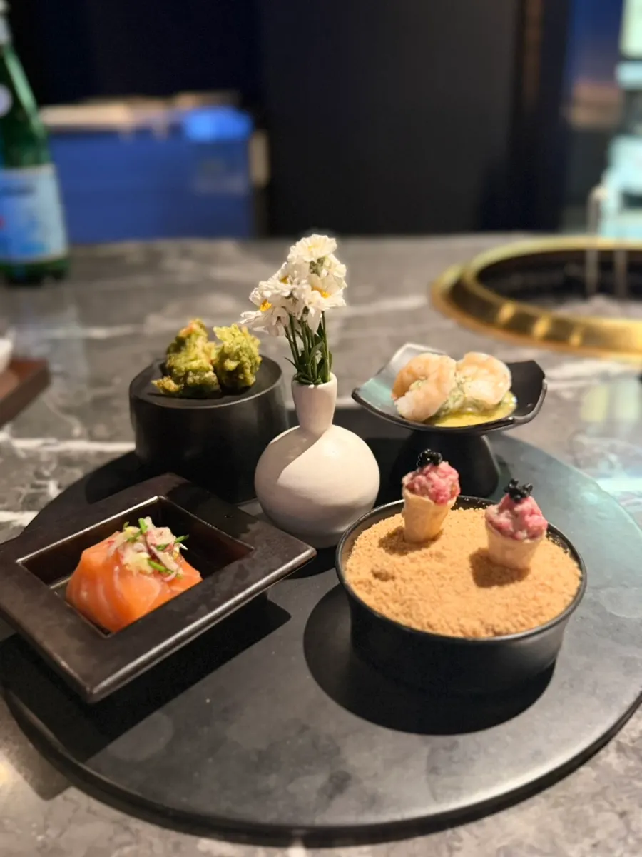 Plating of 4 bite-sized dishes including salmon and yukhoe corn roll