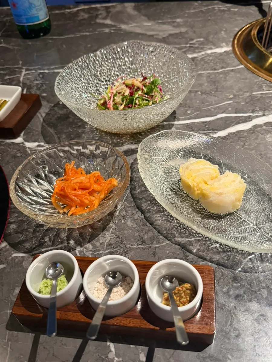 Side dish spread with white kimchi, radish salad, and three sauces