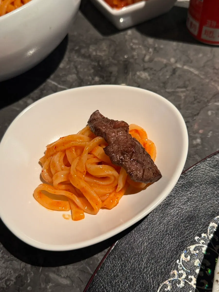 Bibim guksu topped with a piece of meat
