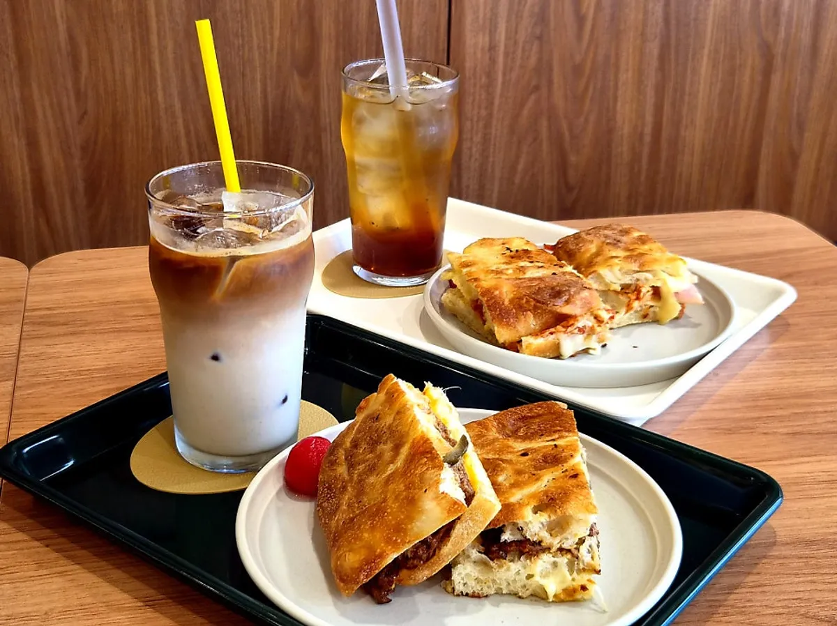 Two types of grill sandwiches and drinks laid out at Benetto