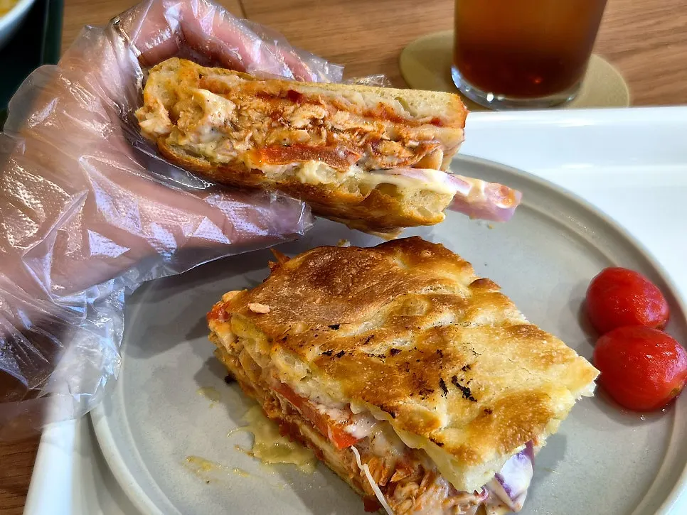 A bite of the BBQ chicken sandwich showing melted cheese