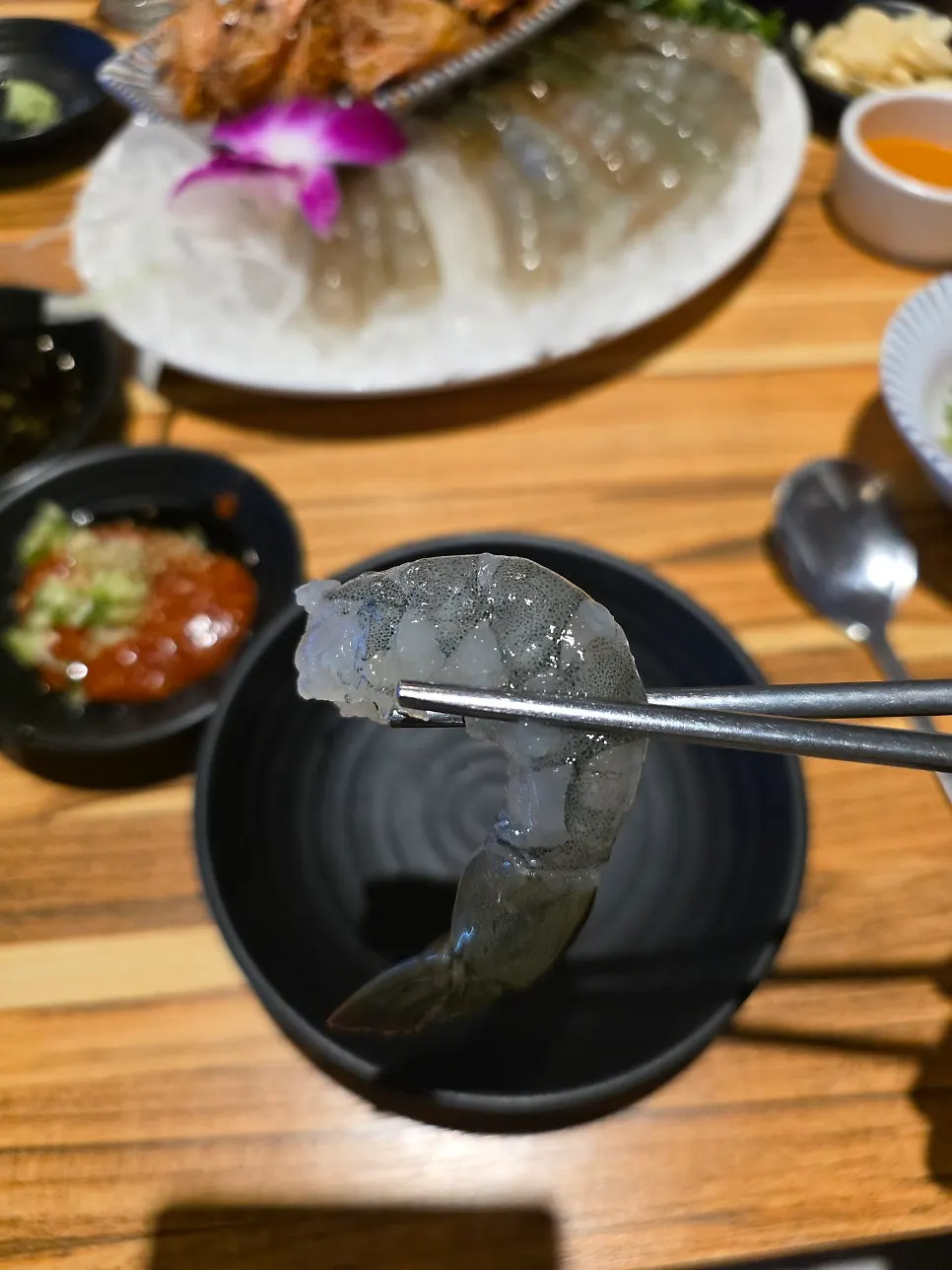 Raw shrimp sashimi dipped in wasabi soy sauce