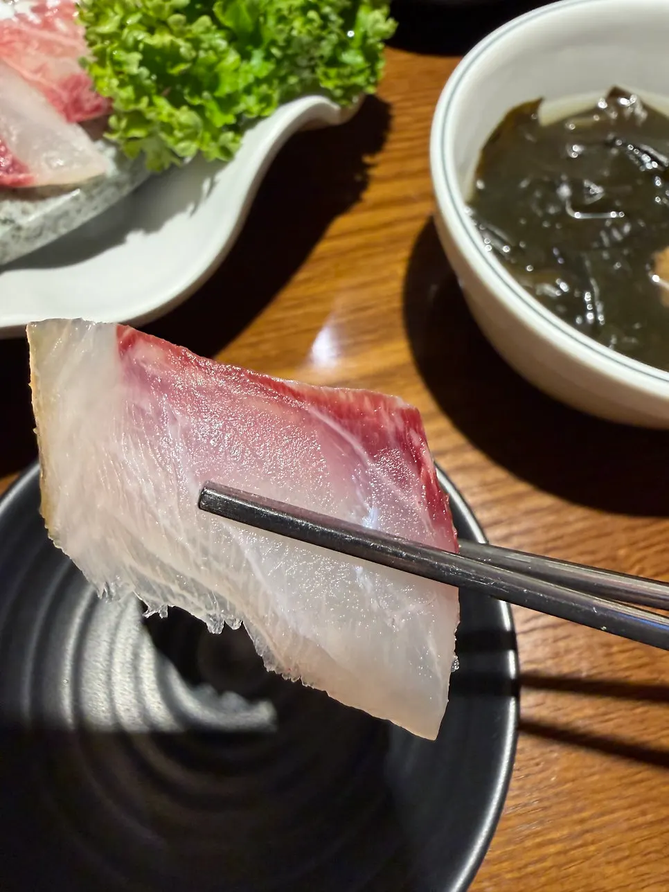 A piece of assorted sashimi wrapped in perilla leaf
