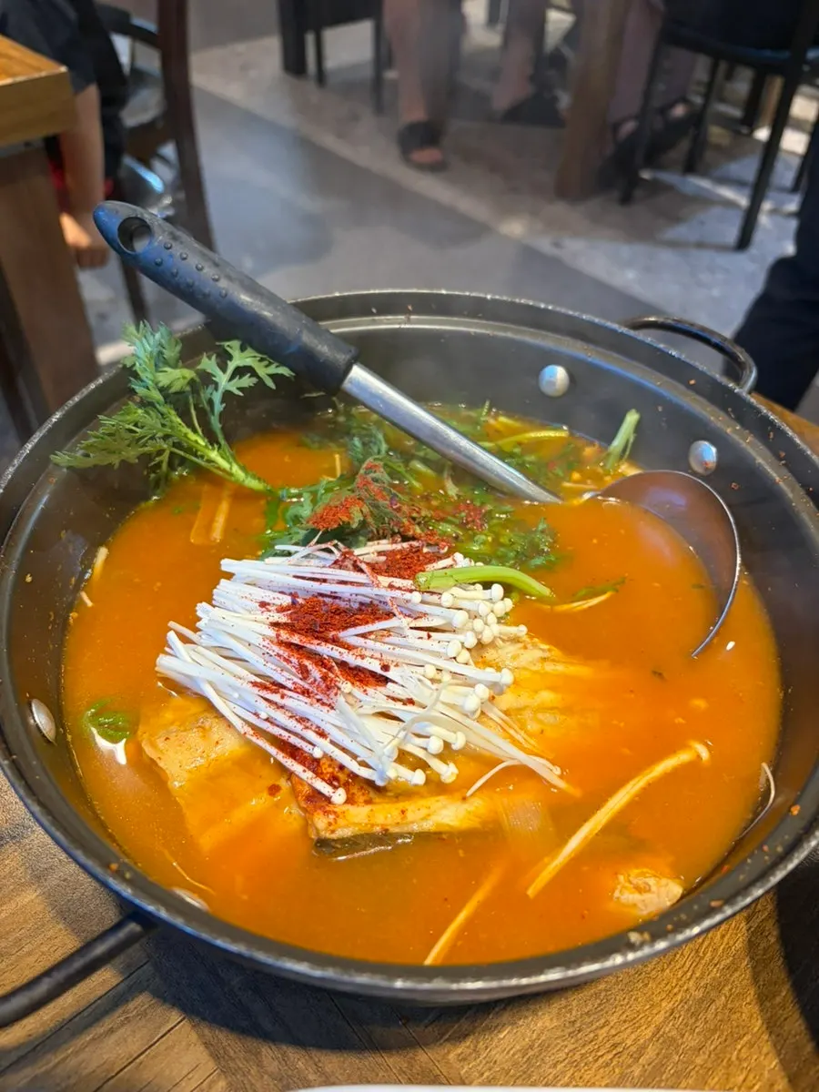 A piece of raw shrimp sashimi dipped in chojang sauce
