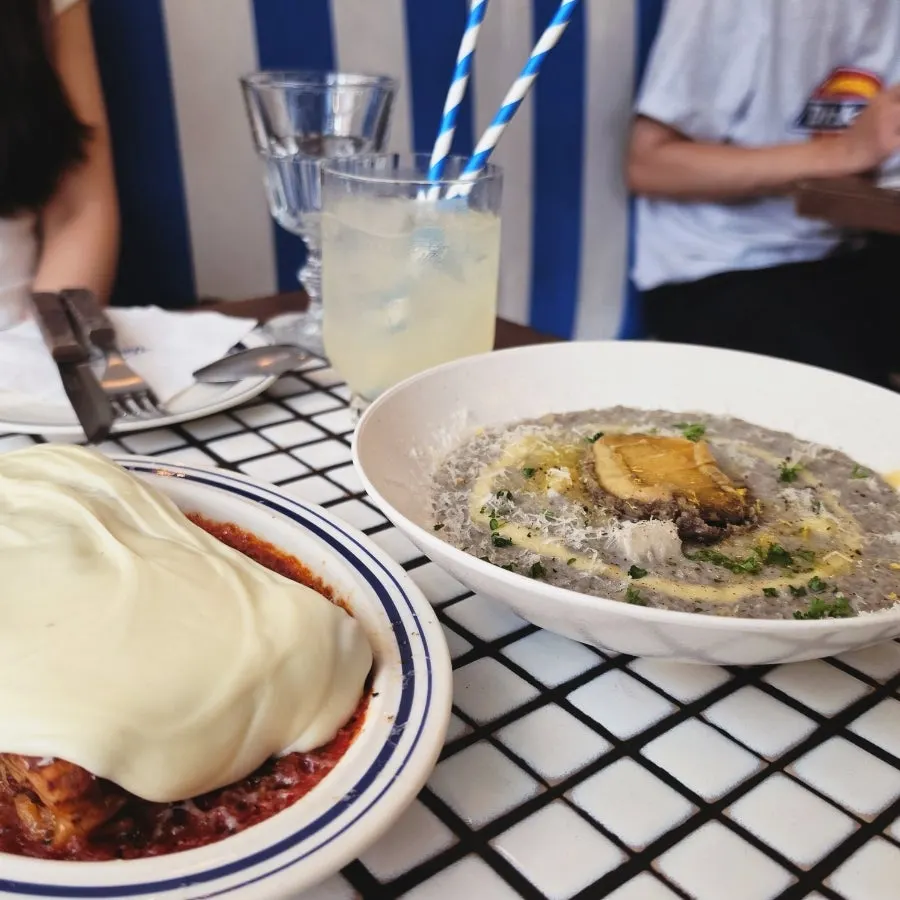Table set with aligot cheese lasagna and abalone squid ink risotto