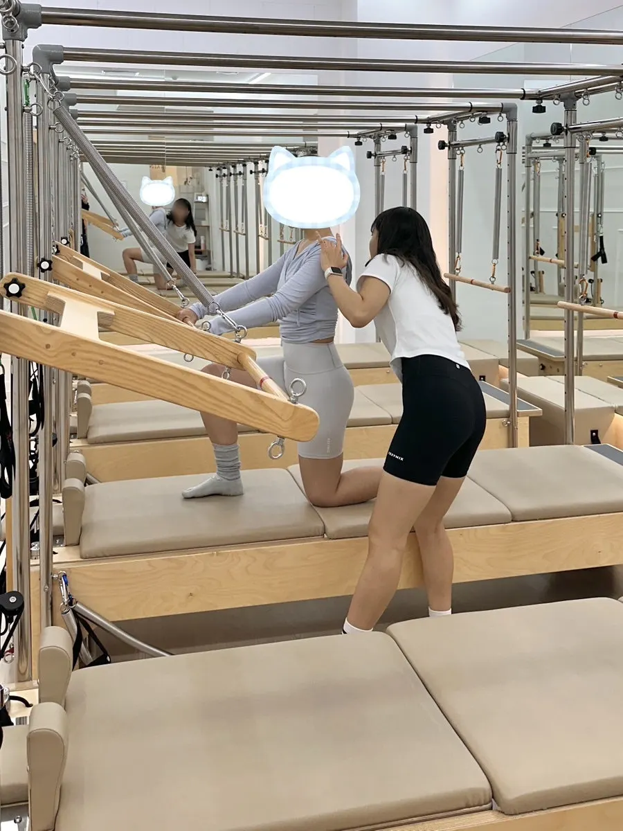 A member receiving posture guidance during a group Pilates class
